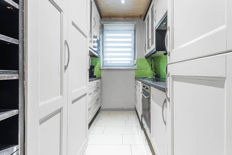 I Na predaj 2-i byt s terasou v Auersthal (Rakúsko) - Kuchyňa v 2-izbovom byte s bielymi skrinkami, zeleným obkladom a svetlou podlahou.