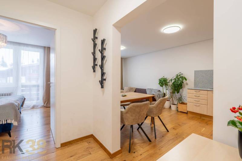 Exkluzívny byt v srdci Vysokých Tatier na Štrbskom Plese - Interiér Rekreačného apartmánu s podlahou s dreveným dekorom, jedálňou a spálňou.