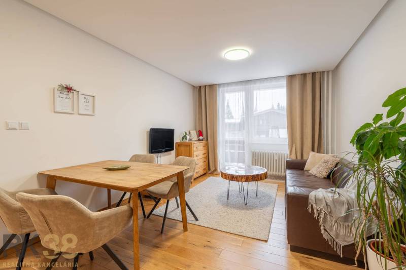 Exkluzívny byt v srdci Vysokých Tatier na Štrbskom Plese - Obývacia izba v rekreačnom apartmáne s útulnou pohovkou a podlahou s dreveným dekorom.