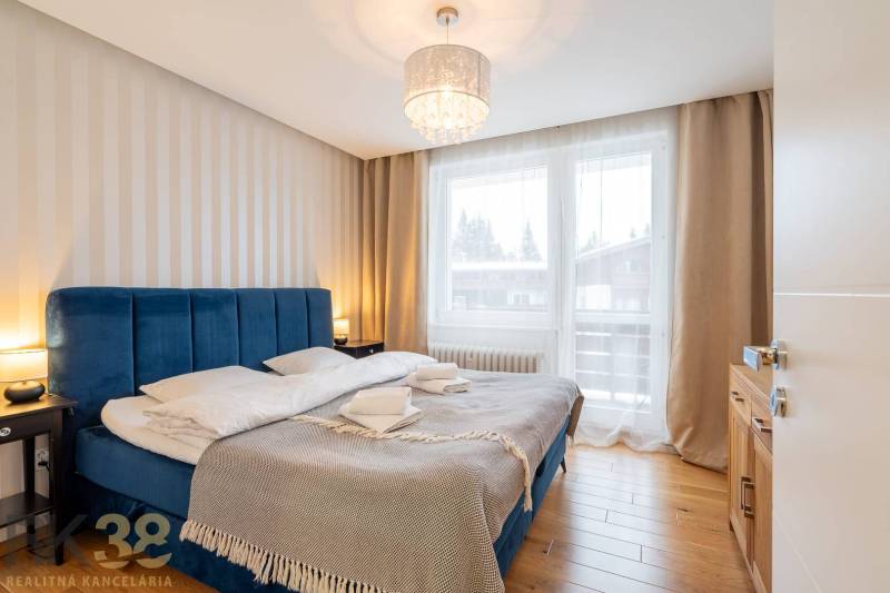 Exkluzívny byt v srdci Vysokých Tatier na Štrbskom Plese - Spálňa v Rekreačnom apartmáne s pohodlnou posteľou a podlahou s dreveným dekorom.