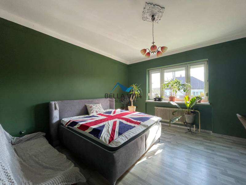 EXKLUZÍVNE - Útulný 3-izbový dom v Čiernom Brode s veľkým pozemkom - Spálňa v rodinnom dome s posteľou, zelenými stenami a podlahou s dreveným dekorom.