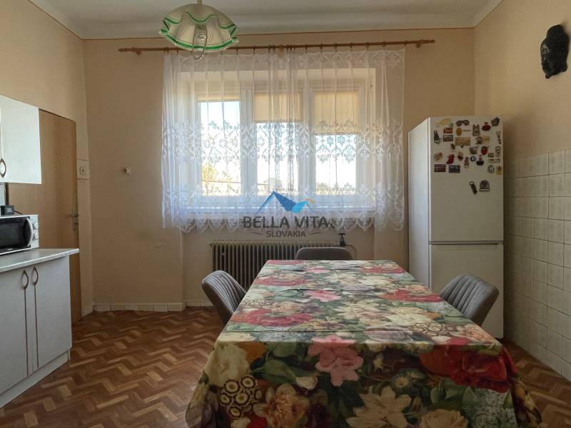 EXKLUZÍVNE - Útulný 3-izbový dom v Čiernom Brode s veľkým pozemkom - Kuchyňa v rodinnom dome s podlahou s dreveným dekorom a kvetinovým obrusom na stole.