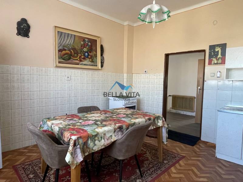 EXKLUZÍVNE - Útulný 3-izbový dom v Čiernom Brode s veľkým pozemkom - Kuchyňa v rodinnom dome s kvetinovým obrusom, stoličkami a podlahou s dreveným dekorom.