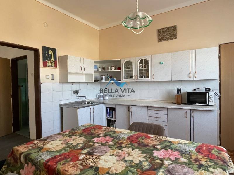 EXKLUZÍVNE - Útulný 3-izbový dom v Čiernom Brode s veľkým pozemkom - Kuchyňa v rodinnom dome s kvetinovým obrusom, bielymi skrinkami a farebnými stenami.