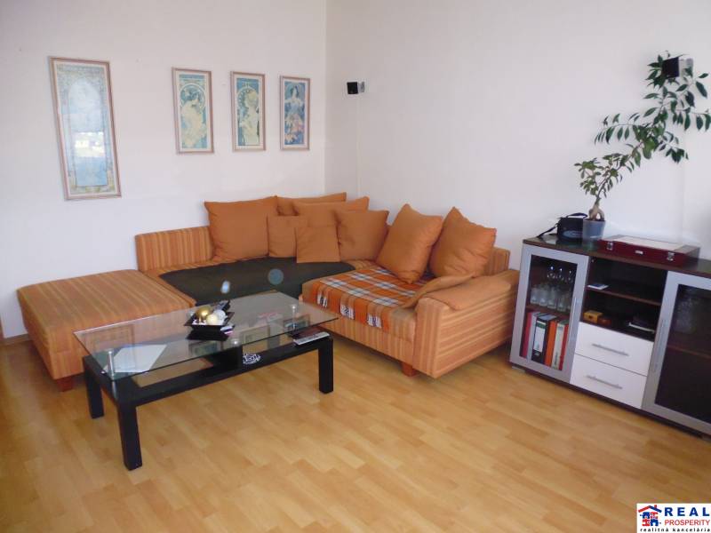 PRENÁJOM: M.NEŠPORA - 2-izbový byt, 58 m2, 7.posch. - Sídlisko III. - Obývacia izba v 2-izbovom byte so sedačkou a stolíkom na podlahe s dreveným dekorom.