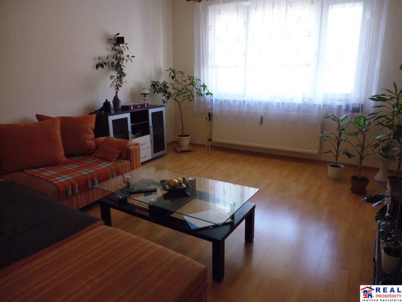 PRENÁJOM: M.NEŠPORA - 2-izbový byt, 58 m2, 7.posch. - Sídlisko III. - Obývačka v 2-izbovom byte s podlahou s dreveným dekorom a pohodlnou sedačkou.