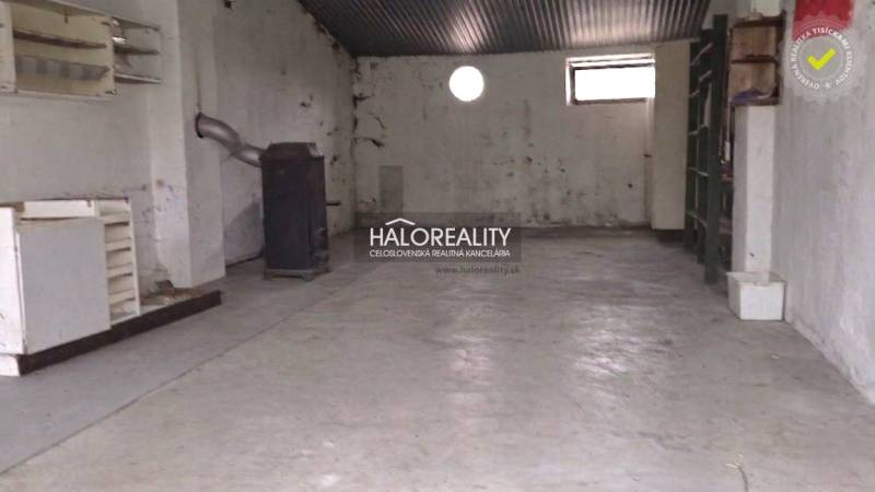Predaj, chalupa Poltár - EXKLUZÍVNE HALO REALITY - Priestor v chate s jednoduchým kachľovým sporákom a oknami.