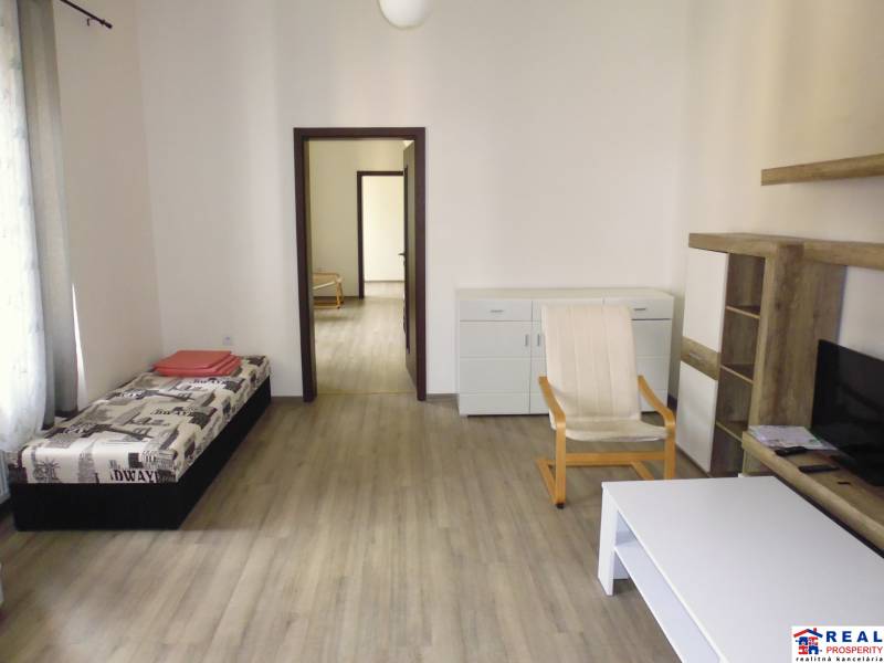 PRENÁJOM: HLAVNÁ - VOĽNÝ 2,5-izbový byt + kuchyňa, kúpeľňa, WC  - Obývacia izba v 3-izbovom byte s podlahou s dreveným dekorom a svetlým nábytkom.