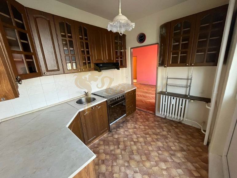 3-izb. byt, Ružinov, Šalviová, lodžia, 3.p./9 - Kuchyňa v 3-izbovom byte s tmavými skrinkami a vstavanými spotrebičmi, podlaha s dreveným dekorom.