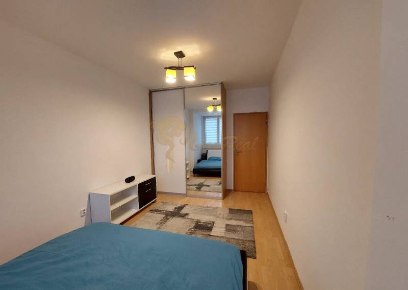 4-izb. byt na ul. Wolkrova, Petržalka, upravený na 2 bytové jednotky - Spálňa so vstavanou skriňou, posteľou a podlahou s dreveným dekorom v 4-izbovom byte.