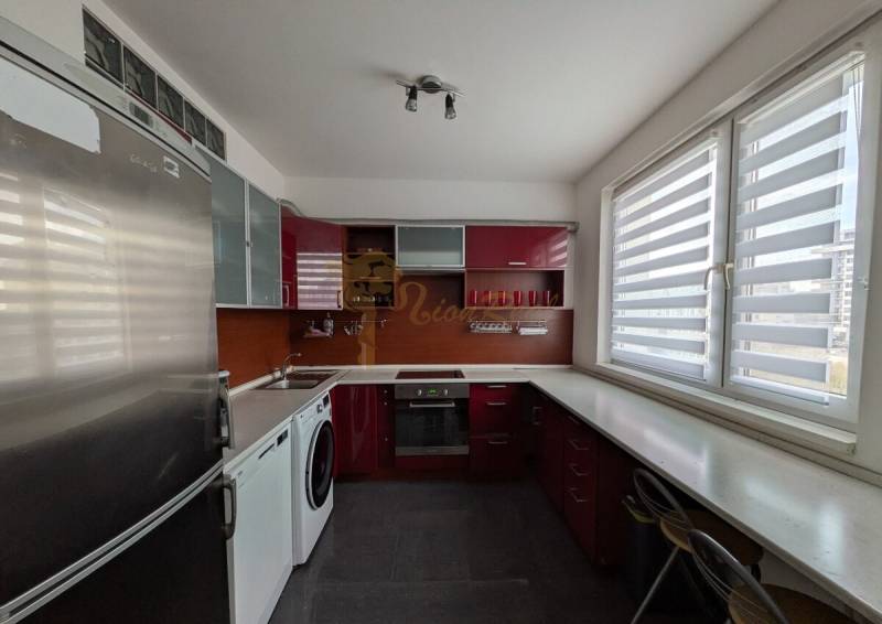 4-izb. byt na ul. Wolkrova, Petržalka, upravený na 2 bytové jednotky - Kuchyňa s červenými skrinkami, spotrebičmi a veľkými oknami v 4-izbovom byte.