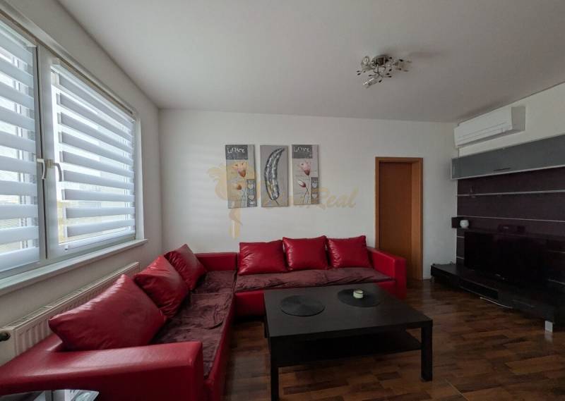 4-izb. byt na ul. Wolkrova, Petržalka, upravený na 2 bytové jednotky - Obývacia izba so sedačkou, stolíkom a podlahou s dreveným dekorom v 4-izbovom byte.