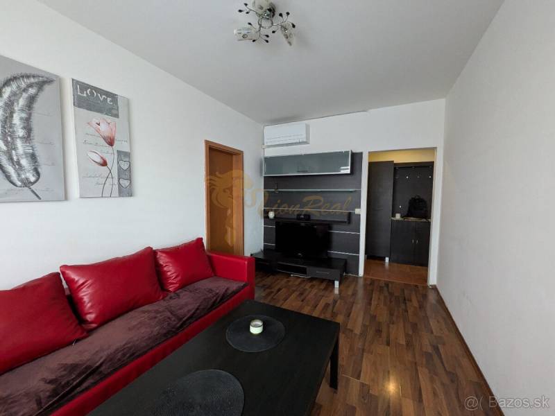 4-izb. byt na ul. Wolkrova, Petržalka, upravený na 2 bytové jednotky - Obývačka 4-izbového bytu s červenou sedačkou a podlahou s dreveným dekorom.