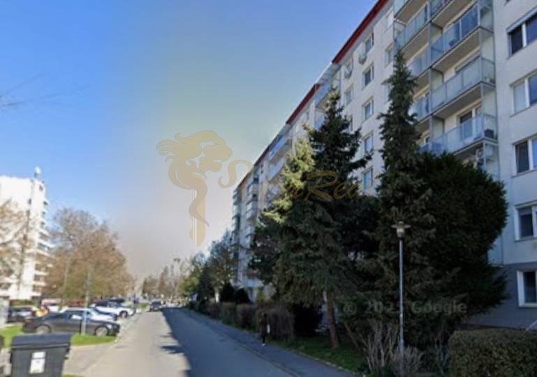 Garzónka, Jašíkova, Ružinov, pôvodný stav - Bytový dom v Bratislave - Ružinove na Jašíkovej ulici pri ceste s autami a stromami.