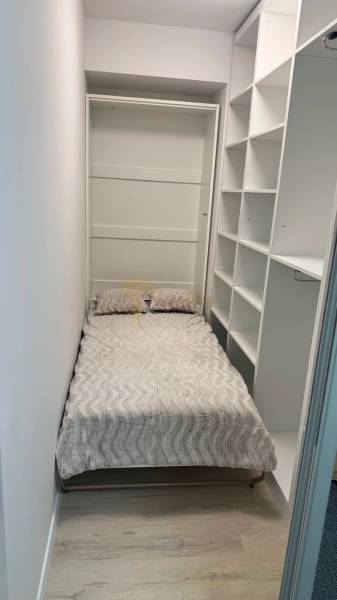 Novostavba 2,5-izb. bytu v NUPPU, garážové státie + vonkajšie státie - Úzka spálňa v 2-izbovom byte s posteľou a otvorenými policami.