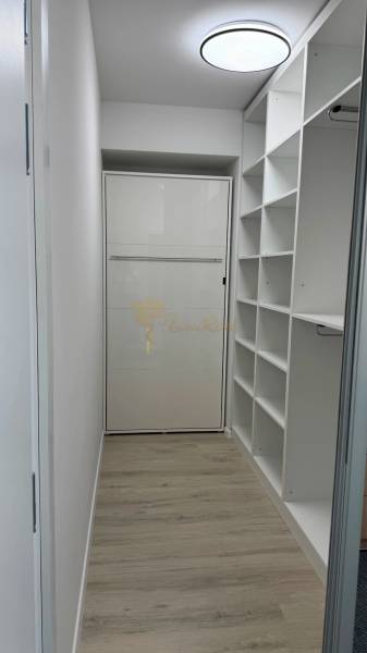 Novostavba 2,5-izb. bytu v NUPPU, garážové státie + vonkajšie státie - Minimalistický úložný priestor v 2-izbovom byte s podlahou s dreveným dekorom.