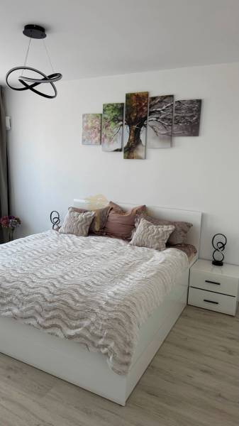 Novostavba 2,5-izb. bytu v NUPPU, garážové státie + vonkajšie státie - Spálňa s posteľou, nočnými stolíkmi a podlahou s dreveným dekorom v 2-izbovom byte.