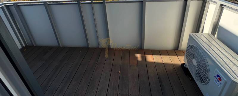 Novostavba 2,5-izb. bytu v NUPPU, garážové státie + vonkajšie státie - Balkón s podlahou s dreveným dekorom a klimatizačnou jednotkou v 2-izbovom byte.