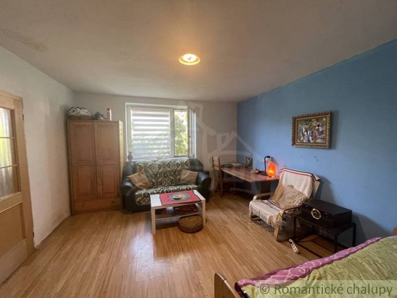 Trojizbový rodinný dom vhodný aj na chalupu v kľudnej časti obce Jatov - Izba v rodinnom dome s podlahou s dreveným dekorom, gaučom a stolíkom.