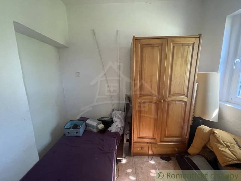 Trojizbový rodinný dom vhodný aj na chalupu v kľudnej časti obce Jatov - Izba v rodinnom dome s posteľou, drevenou skriňou a oknom.