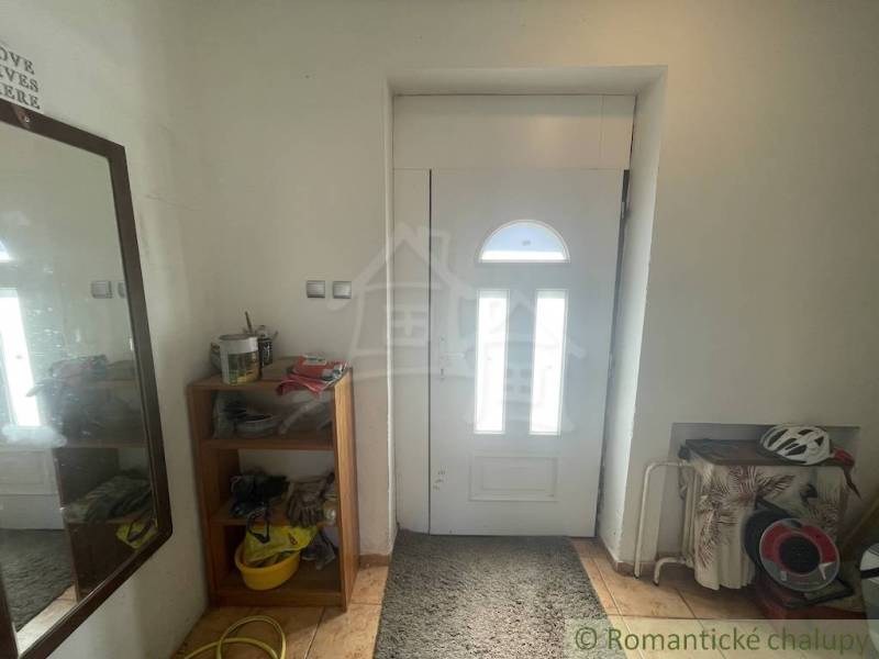 Trojizbový rodinný dom vhodný aj na chalupu v kľudnej časti obce Jatov - Predsieň rodinného domu s bielymi dverami, zrkadlom a dreveným dekorom podlahy.