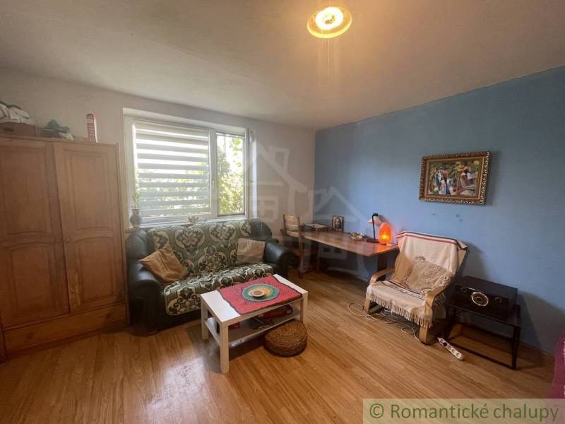 Trojizbový rodinný dom vhodný aj na chalupu v kľudnej časti obce Jatov - Obývacia izba so sedačkou a podlahou s dreveným dekorom v rodinnom dome.