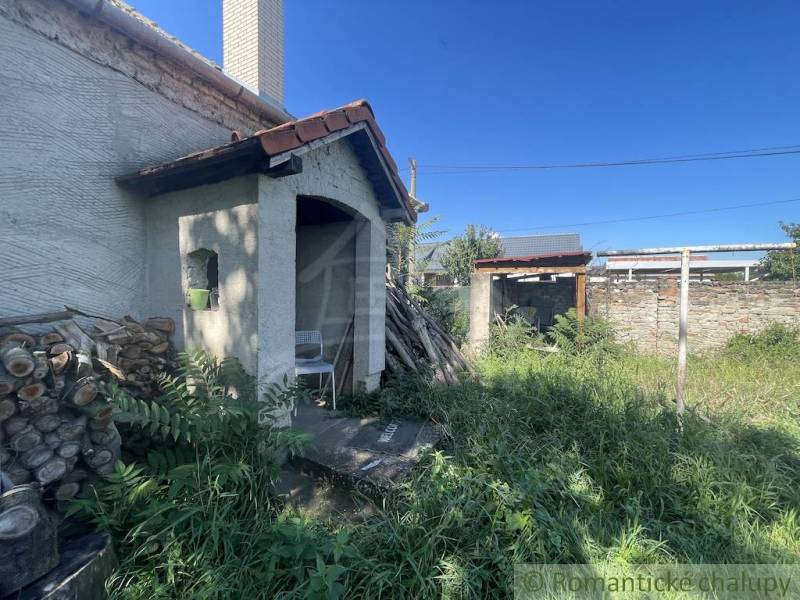 Trojizbový rodinný dom vhodný aj na chalupu v kľudnej časti obce Jatov - Zarastený dvor rodinného domu v Jatove s dreveným skladom palivového dreva.