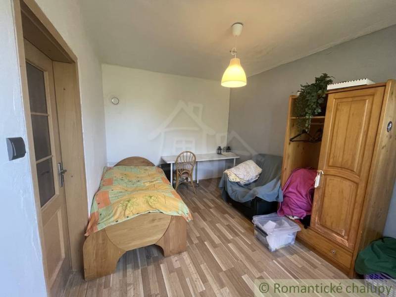 Trojizbový rodinný dom vhodný aj na chalupu v kľudnej časti obce Jatov - Izba v rodinnom dome s posteľou, stolom a podlahou s dreveným dekorom.