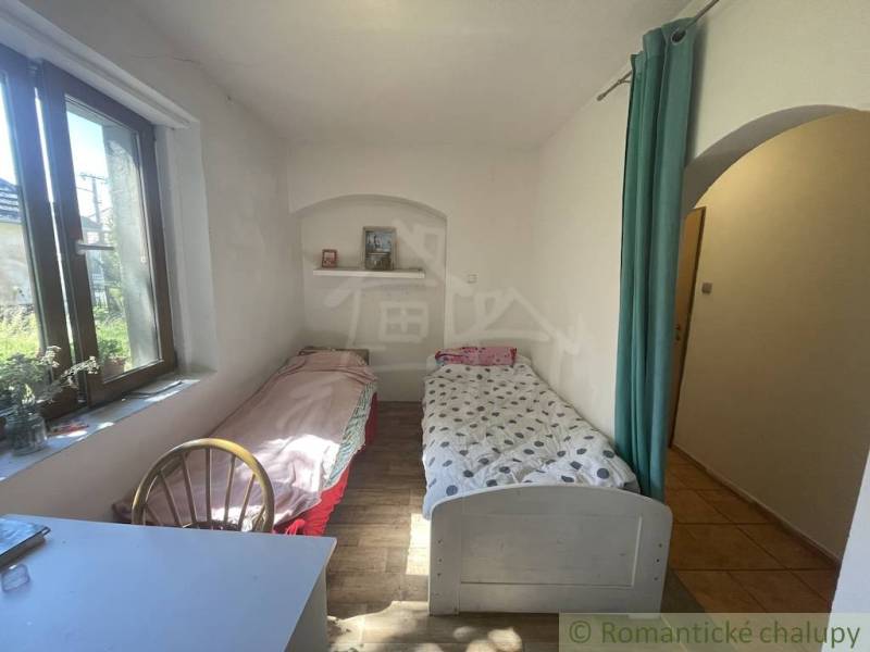 Trojizbový rodinný dom vhodný aj na chalupu v kľudnej časti obce Jatov - Izba v rodinnom dome s dvoma posteľami, podlahou s dreveným dekorom a oknom.