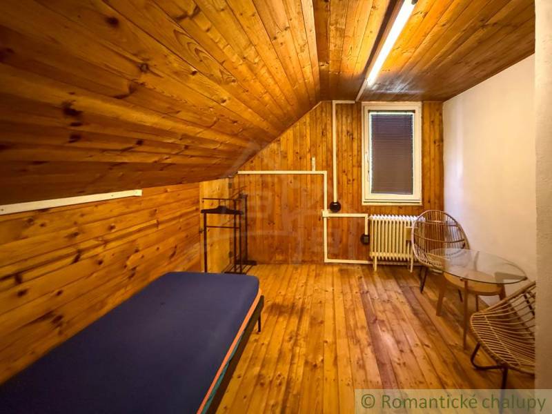 Chalupa - rodinný dom v krásnom prostredí – Moštenica, Banská Bystrica - Interiér chaty s podlahou s dreveným dekorom, posteľ a kreslá pre pohodlie.