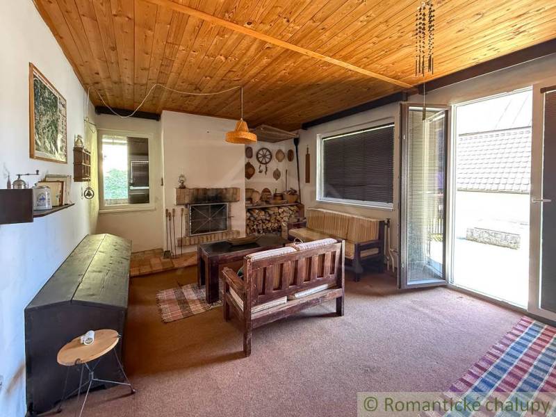 Chalupa - rodinný dom v krásnom prostredí – Moštenica, Banská Bystrica - Interiér chaty s dreveným stropom, sedacou súpravou a krbom, s výhľadom do záhrady.
