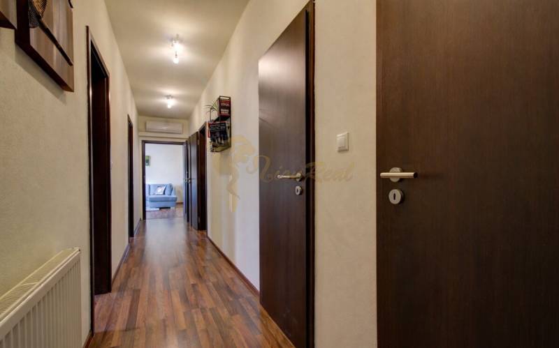 5-izb. byt, Krajinská, Podunajské Biskupice, 2.p./3 - Chodba s podlahou s dreveným dekorom v 5 a viac izbovom byte, dvere a sedačka.