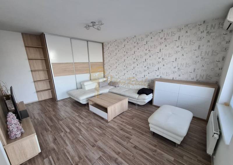 3-izb. byt, Nevädzová ul., Ružinov, Retro - Obývačka 3-izbového bytu s podlahou s dreveným dekorom, sedačkou a úložným priestorom.