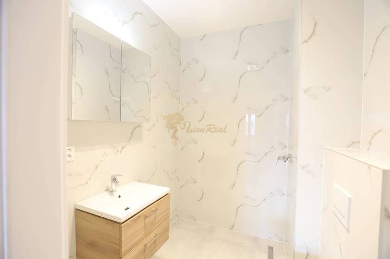 1-izb. byt v novostavbe v Ružinove, 4p./10 - Kúpeľňa v 1-izbovom byte s umývadlom a mramorovým vzorom na stenách.