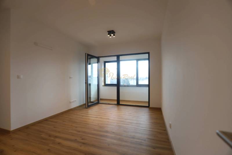 1-izb. byt v novostavbe v Ružinove, 4p./10 - Interiér 1-izbového bytu s podlahou s dreveným dekorom a veľkými oknami.