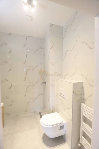 1-izb. byt v novostavbe v Ružinove, 4p./10 - Kúpeľňa v 1-izbovom byte so sprchovacím kútom a toaleta s obkladom v mramorovom dekore.