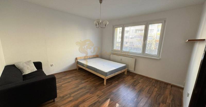 1-izb. byt, J.Stanislava, Karlova Ves, lodžia, 3.p./8 - Jednoizbový byt s rozkladacím gaučom, posteľou a podlahou s dreveným dekorom.