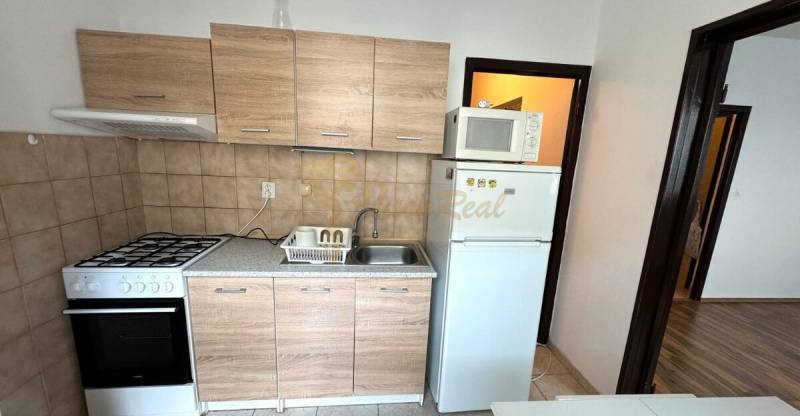 1-izb. byt, J.Stanislava, Karlova Ves, lodžia, 3.p./8 - Kuchyňa v 1-izbovom byte s dreveným dekorom a základným vybavením.