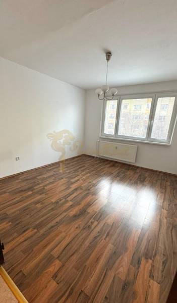 1-izb. byt, J.Stanislava, Karlova Ves, lodžia, 3.p./8 - Priestranná izba s podlahou s dreveným dekorom a veľkým oknom v 1-izbovom byte.