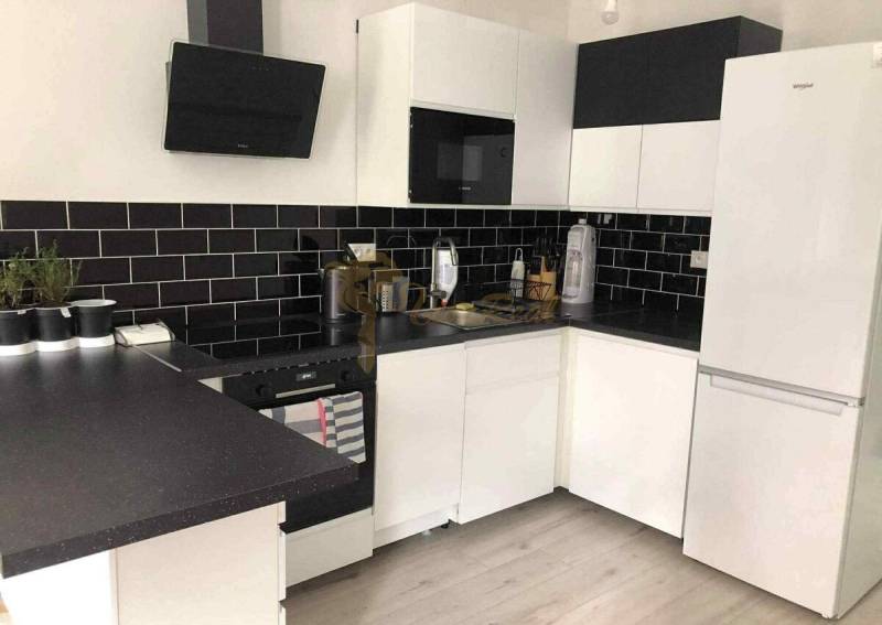 1,5 izb. byt s predzáhradkou, Podunajské Biskupice, projekt Oppidum - Biela kuchyňa s čiernymi obkladmi a podlahou s dreveným dekorom v 2-izbovom byte.