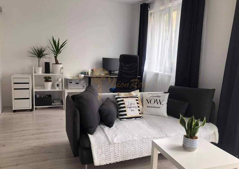 1,5 izb. byt s predzáhradkou, Podunajské Biskupice, projekt Oppidum - Obývacia izba v 2-izbovom byte s tmavými závesmi a dekoratívnymi vankúšmi.