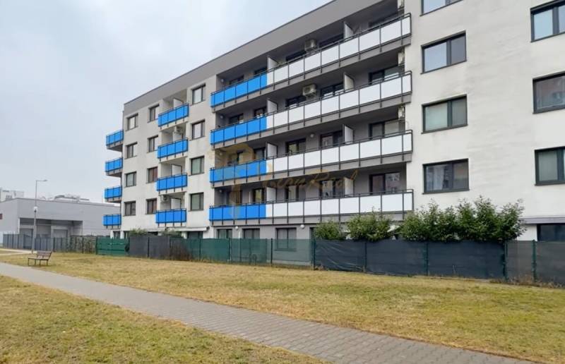 1,5 izb. byt s predzáhradkou, Podunajské Biskupice, projekt Oppidum - Exteriér bytového domu v Bratislave - Podunajské Biskupice s modrými balkónmi a zeleným trávnikom.