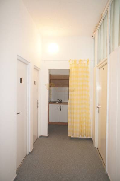Kancelárie, Drieňová ul., Ružinov 25 m2 - Úzka chodba s dverami a žlto-bielym závesom, vedúca ku kuchynskému kútiku v kancelárii.