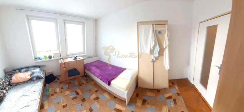 2-izb. byt pri Račianskom Mýte, balkón, 5.p./11 - Spálňa v 2-izbovom byte s posteľou, skriňou a kobercom.