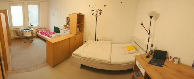 2-izb. byt pri Račianskom Mýte, balkón, 5.p./11 - Spálňa v 2-izbovom byte s dvomi lôžkami, stolom a stenovou výzdobou.