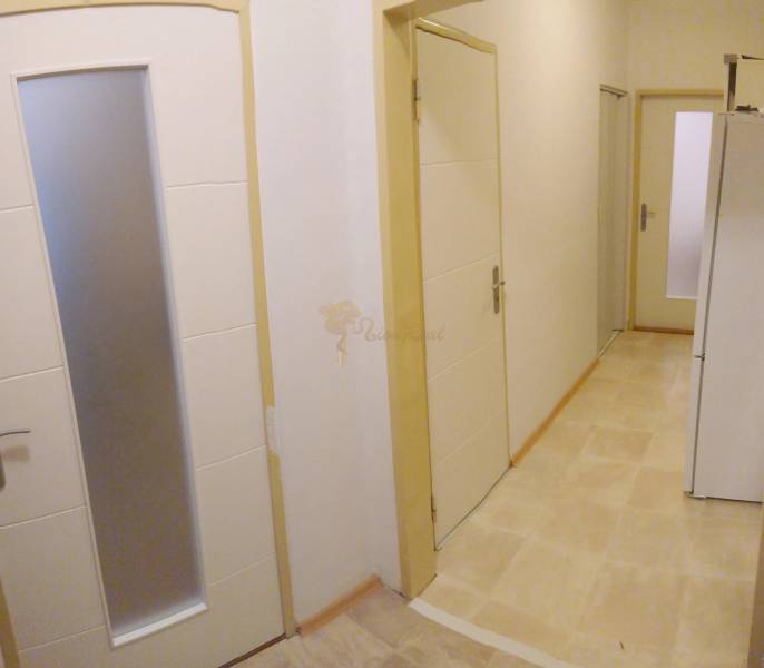 2-izb. byt pri Račianskom Mýte, balkón, 5.p./11 - Chodba v 2-izbovom byte s viacerými dverami a svetlou podlahou.