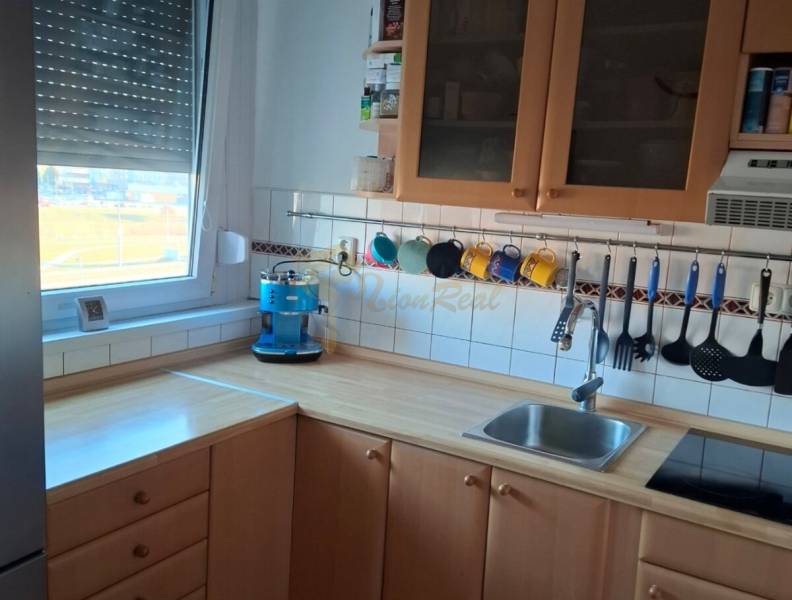 Dvojgarzónka DELUXE, začiatok Petržalky - Kuchyňa v 2-izbovom byte s dreveným dekorom a modrým kávovarom.
