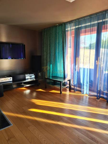 5-izb. dvojpodlažný rodinný dom, Rovinka - Obývacia izba v rodinnom dome s plávajúcom podlahou, televízorom a závesmi prepúšťajúcimi svetlo.