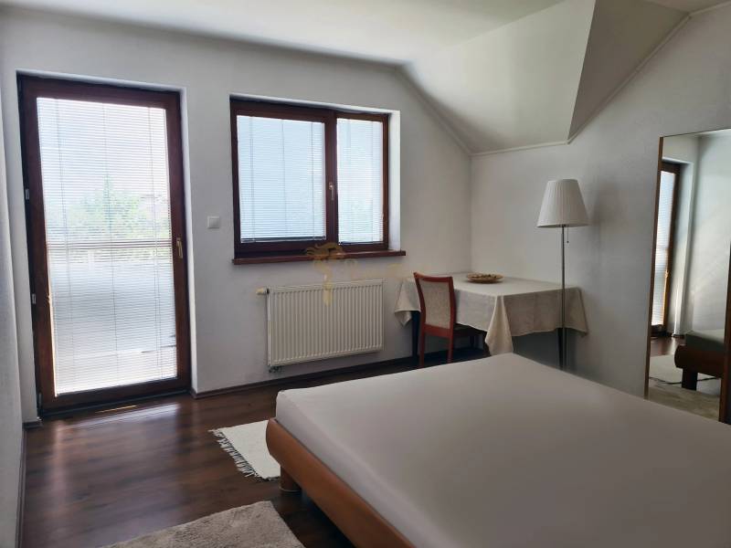 5-izb. dvojpodlažný rodinný dom, Rovinka - Spálňa v rodinnom dome so stolom, postelí a výhľadom cez veľké okná.