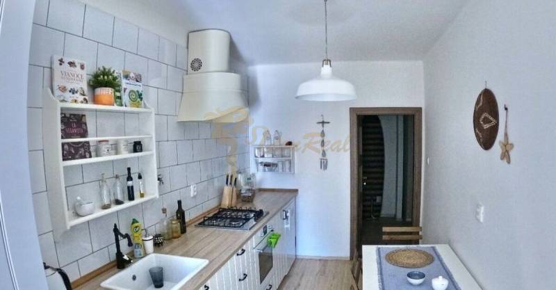 Veľký 2-izb. byt v tehlovom dome, Ružová dolina, Ružinov časť Nivy - Kuchyňa v 2-izbovom byte s podlahou s dreveným dekorom a bielymi skrinkami.